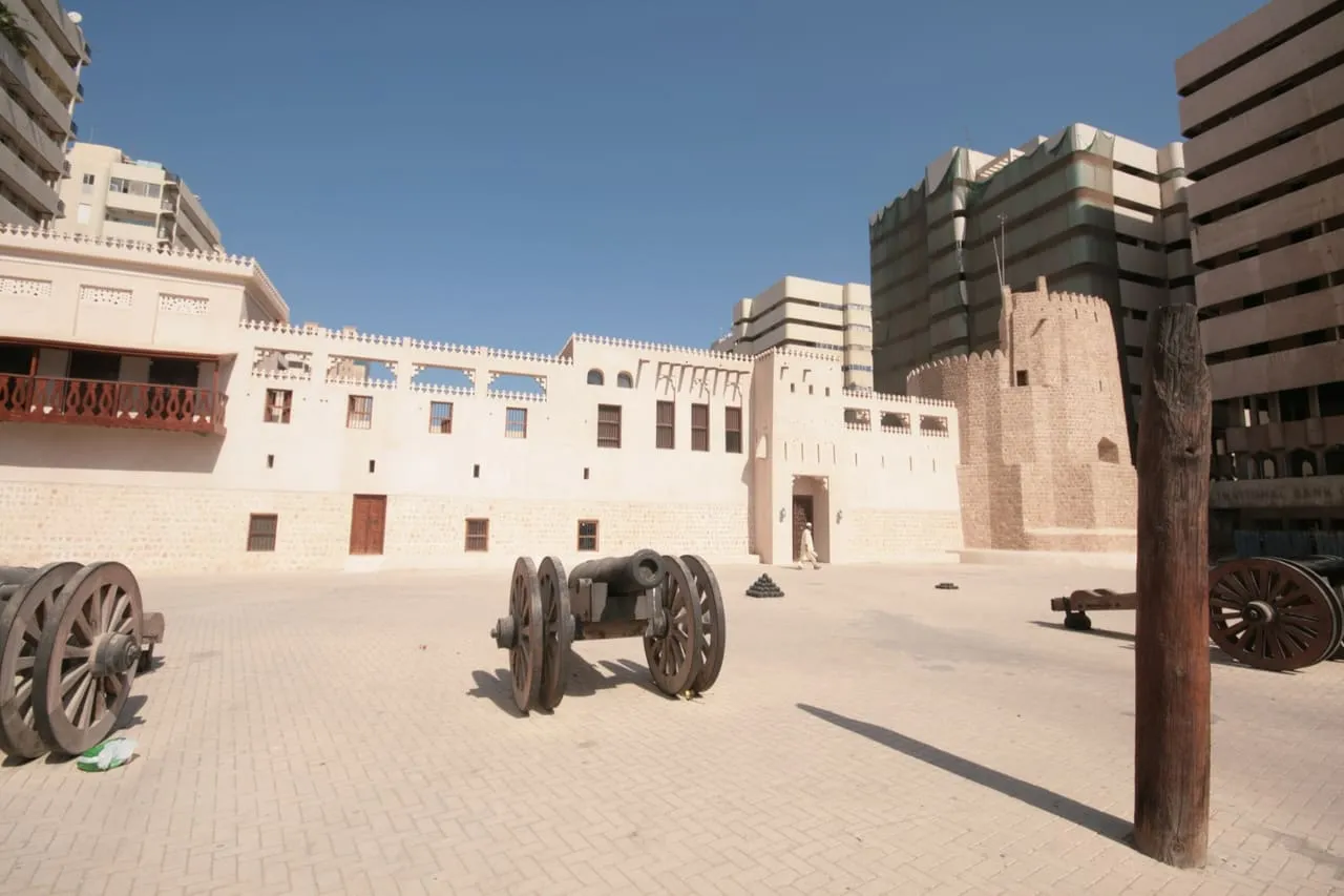 The coral-stone walls and tower of Sharjah Fort (Al Hisn), with old cannons in the square in front