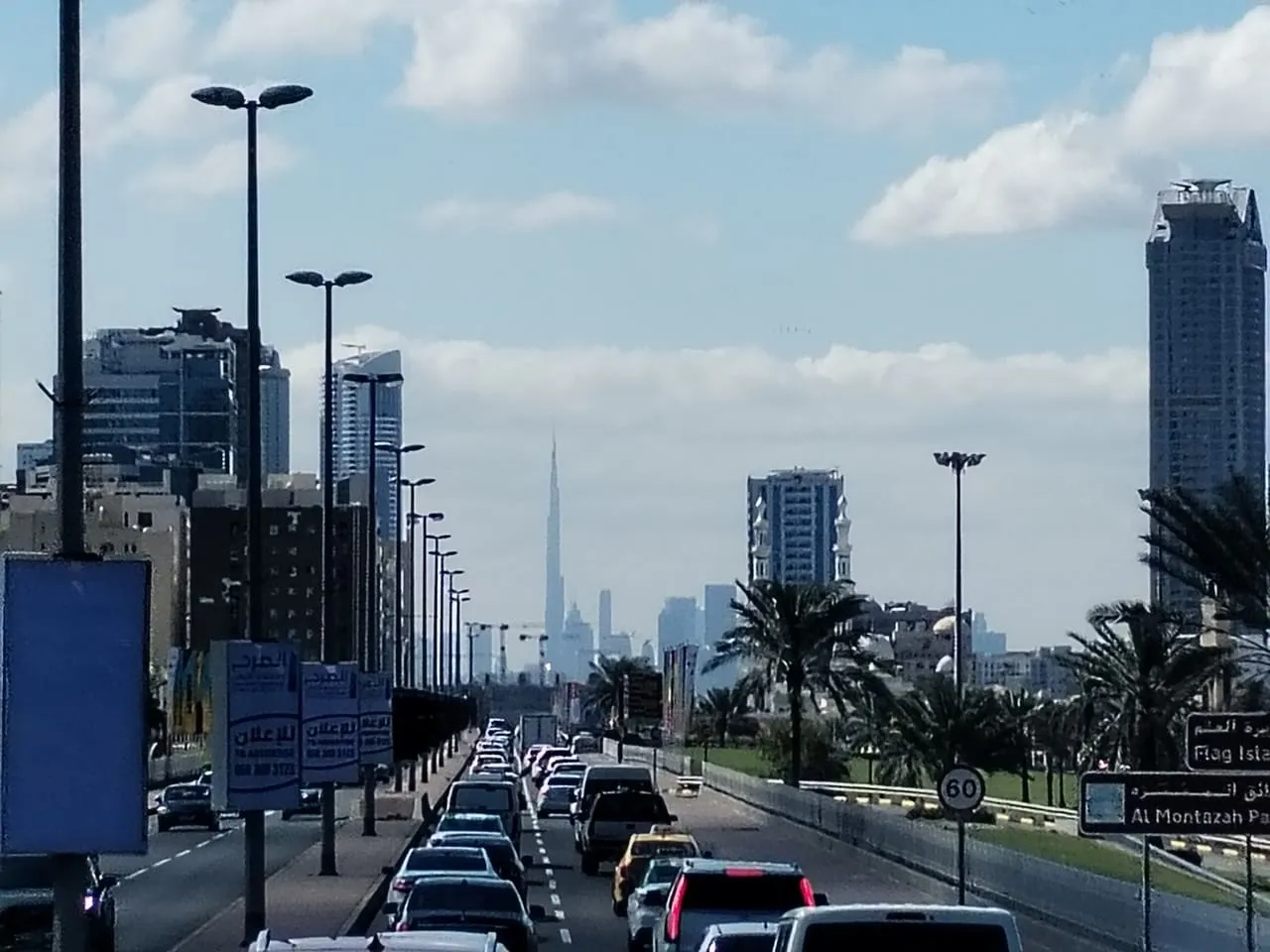 Traffic queued on a road in Sharjah heading towards Dubai, with the Burj Khalifa on the skyline