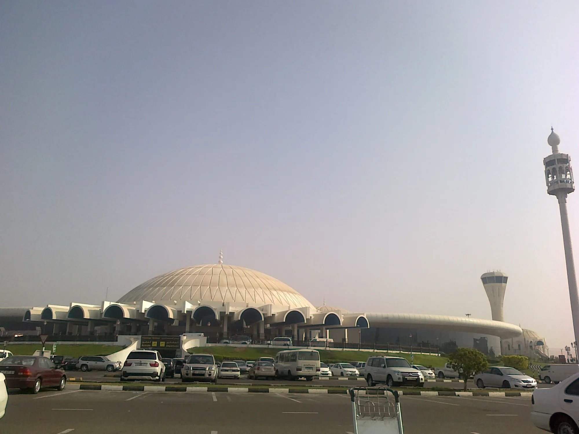 The domed passenger terminal of Sharjah International Airport with its control tower and car park