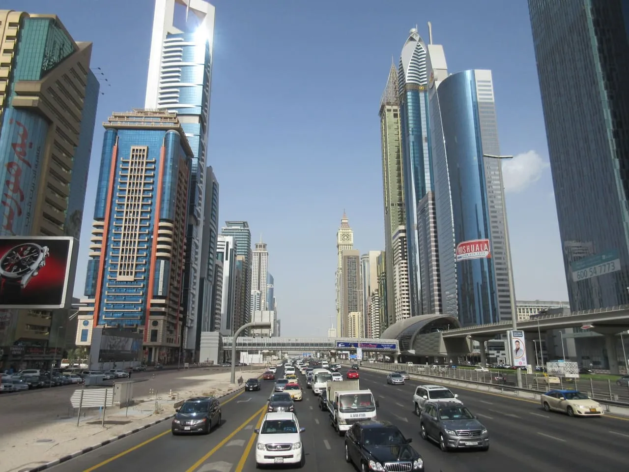 Traffic on Sheikh Zayed Road beside a Dubai Metro station, between the office towers near DIFC