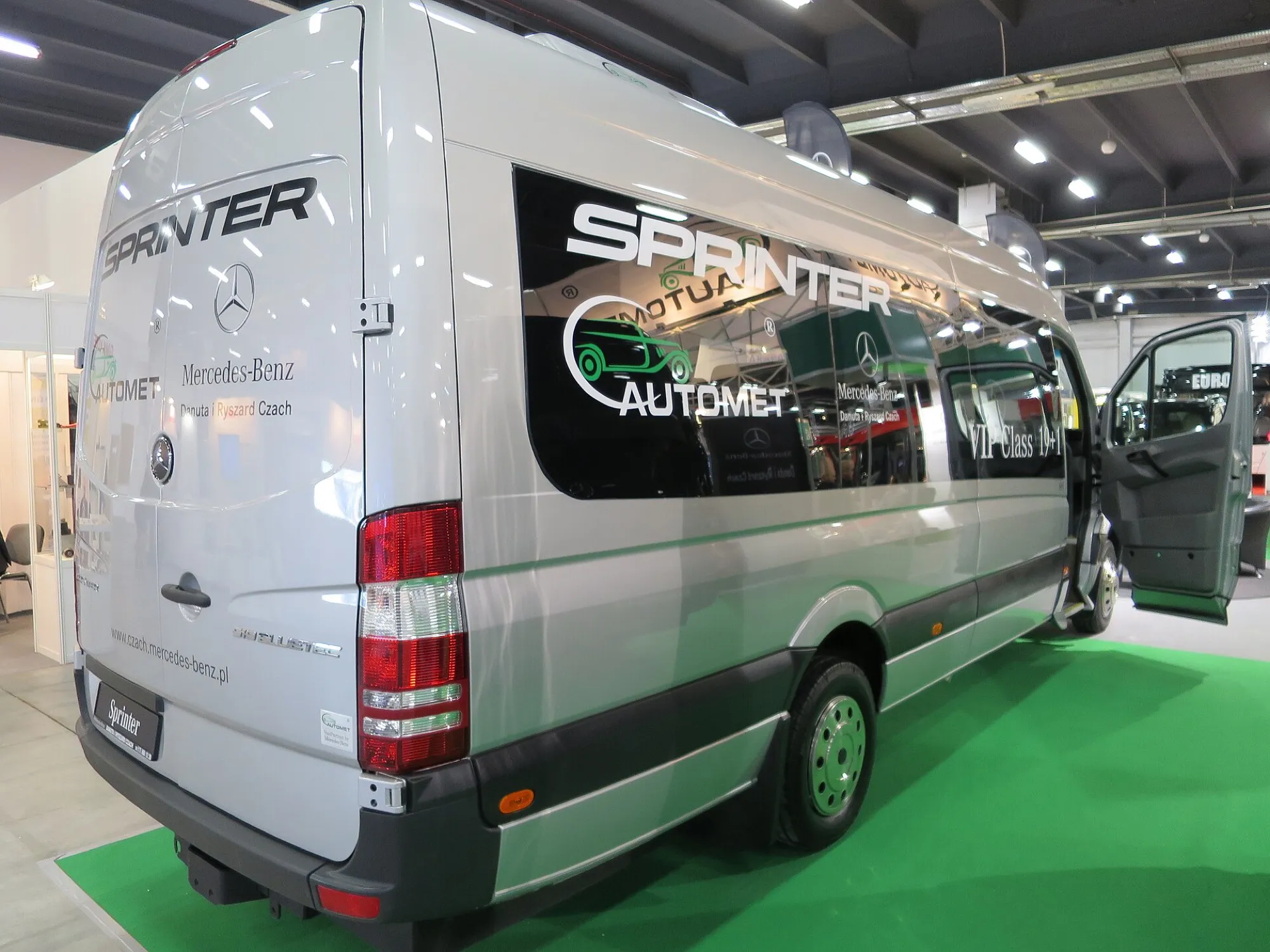 A silver Mercedes-Benz Sprinter minibus in a VIP passenger layout, rear three-quarter view