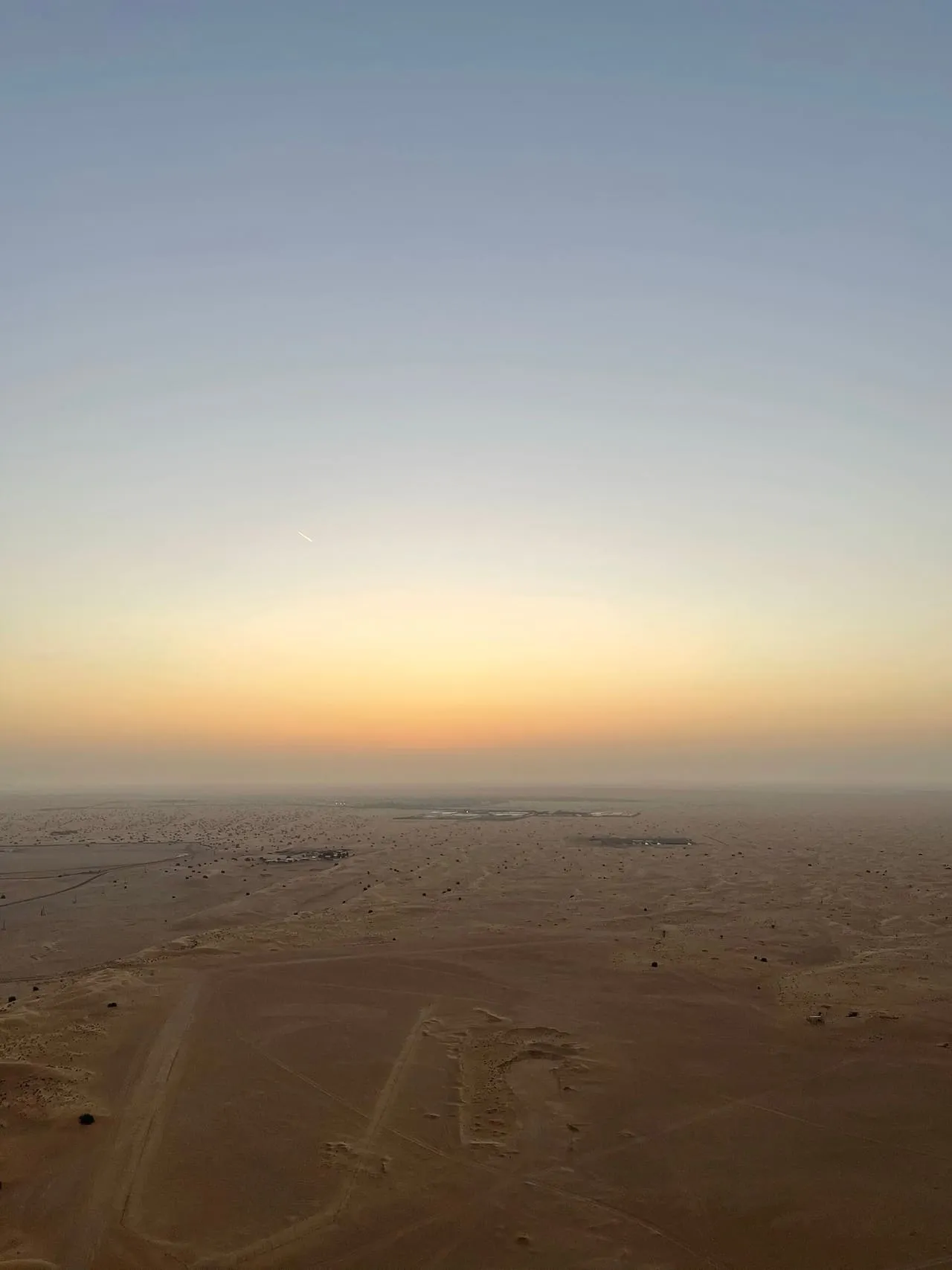 Sunrise over flat desert, seen from a hot air balloon basket above Dubai