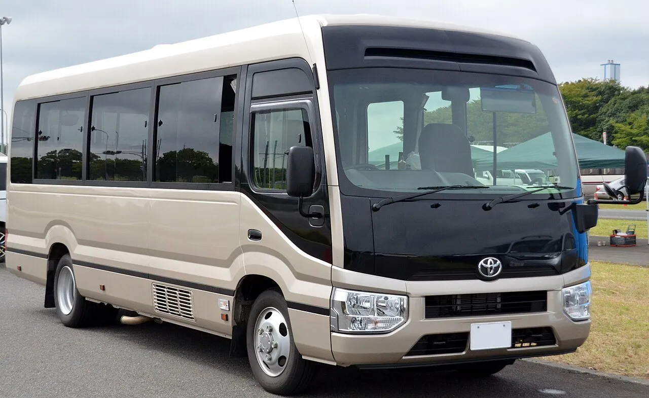 A Toyota Coaster minibus in two-tone beige and black