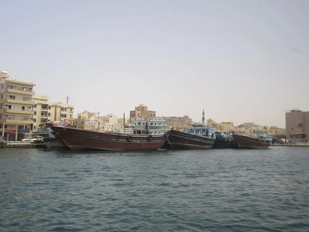 Wooden trading dhows moored side by side along the Dubai Creek wharf