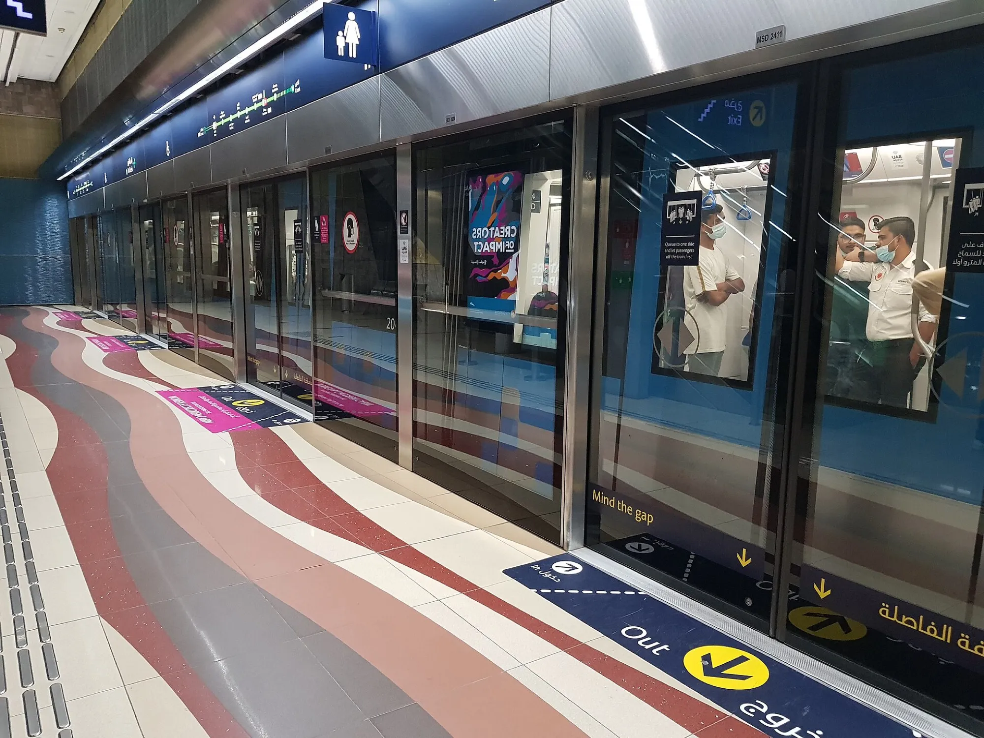 Passengers waiting behind the platform screen doors as a Dubai Metro train arrives