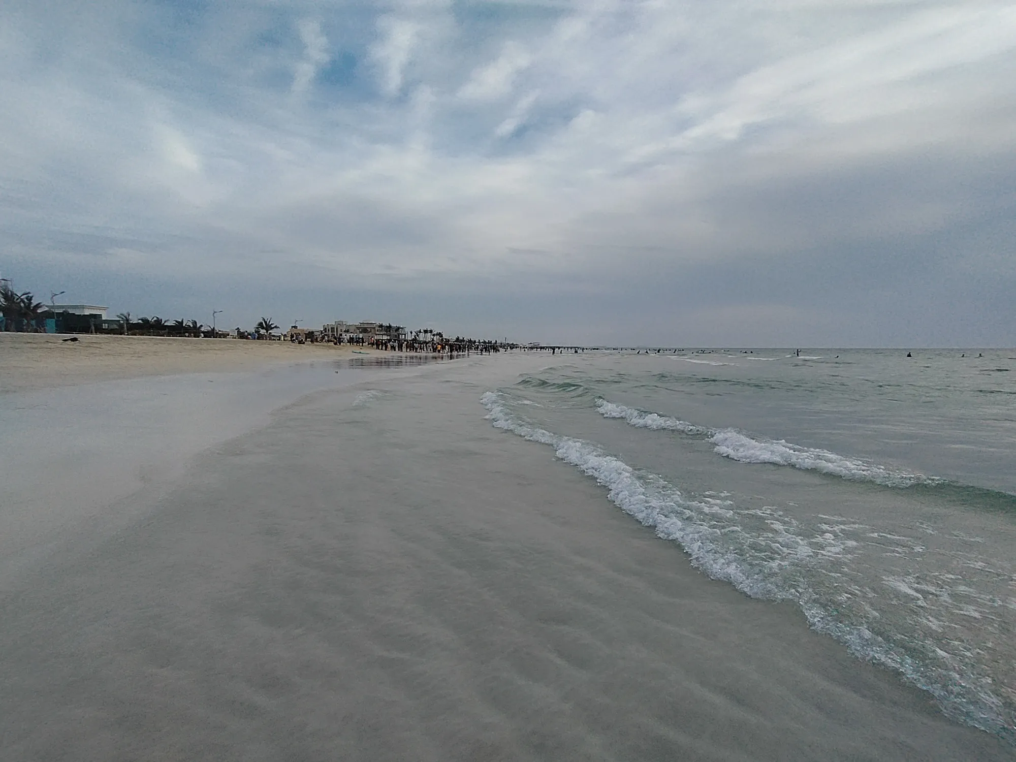 The long sandy beach at Umm Al Quwain under a cloudy sky