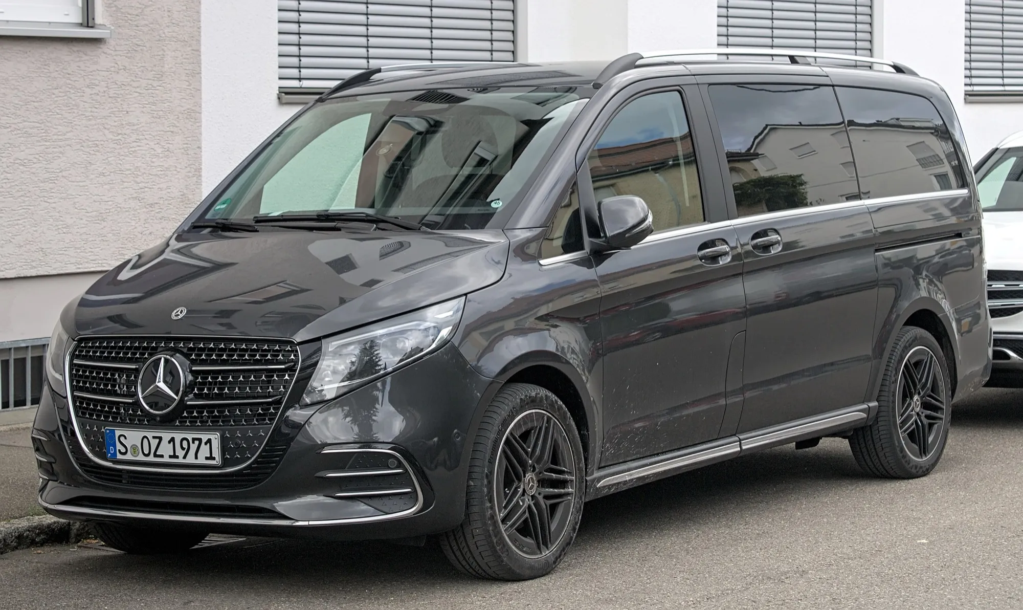 A dark grey Mercedes-Benz V-Class with a sliding side door and roof rails
