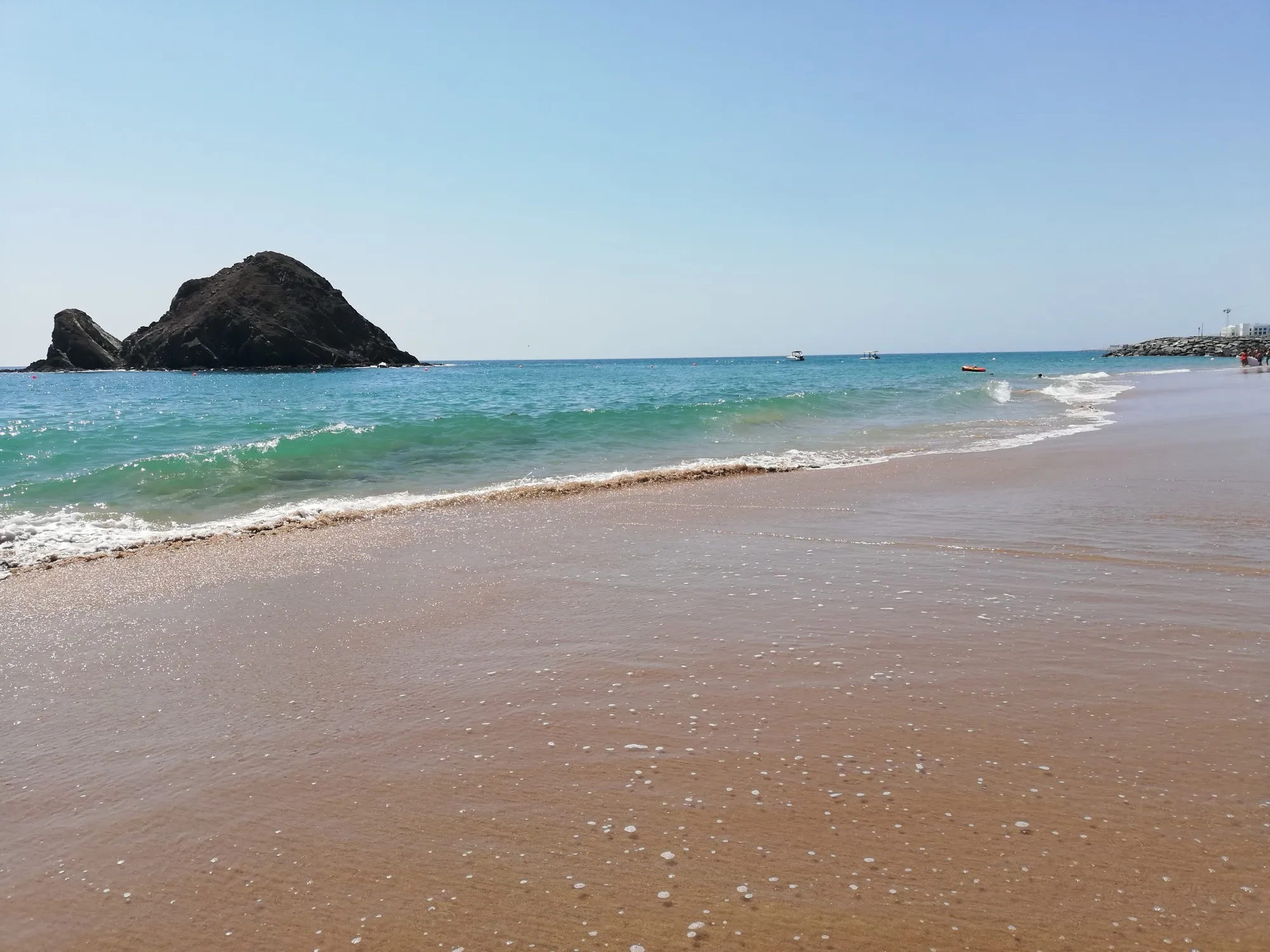 Turquoise surf on the beach at Al Aqah with Snoopy Island offshore