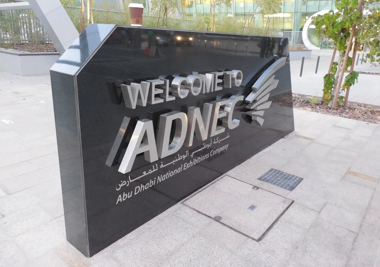 The Welcome to ADNEC sign of the Abu Dhabi National Exhibitions Company on a paved forecourt