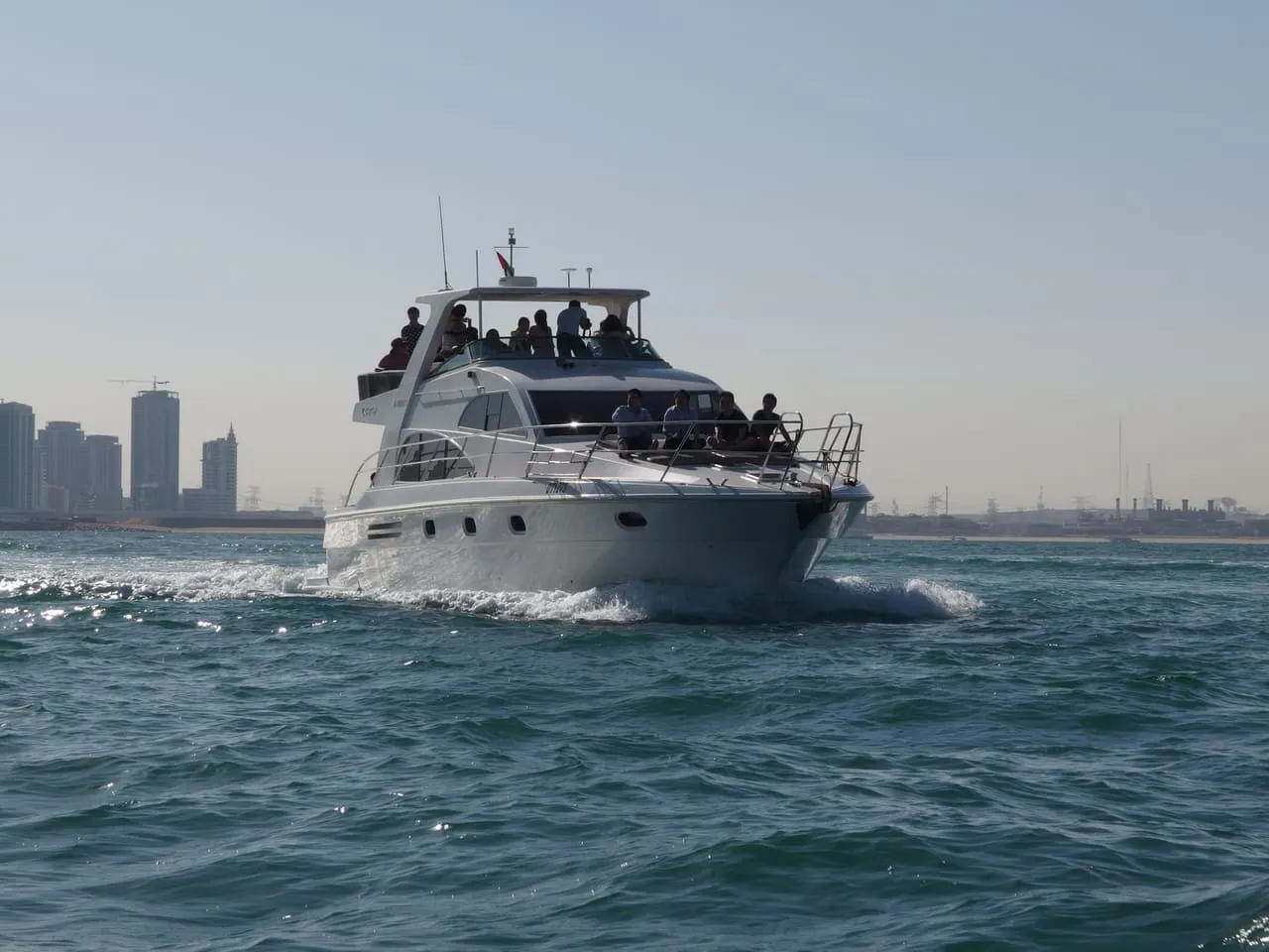 A motor yacht under way in the Gulf off Dubai, with Dubai Marina towers behind